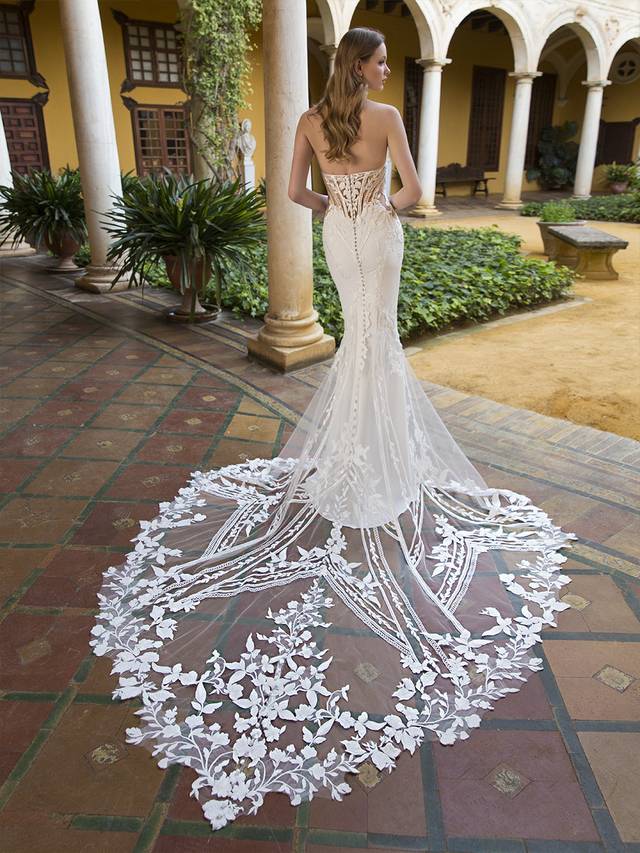 Code: Enzoani Blue Perry This strapless mermaid style is made perfect for our boho bridal babes. The soft sweetheart neckline is embroidered with decadent linear lace. The beautiful crepe fabric is body-contouring while the lace elegantly falls into a floral train. Fall in love with the lined or unlined panel detailing featured on each side of the gown that leads into a sexy and supportive corset-style back. Colour Options: Ivory/Nude OR Ivory/Ivory