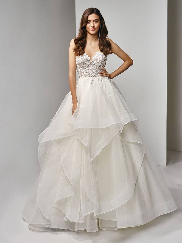 Code: Enzoani Beautiful BT19-09 Code: Enzoani Beautiful BT19-09 The ultimate A-line ball gown for any swoon-worthy moment. The strapless sweetheart neckline bodice is beautifully made of beaded, embroidered and chantilly lace.Specially placed lace appliques daintily drape onto the voluminous tiered, tulle skirt for an added dose of sweet and playful romance.Colour Options: Ivory/Beige OR Ivory/Ivory