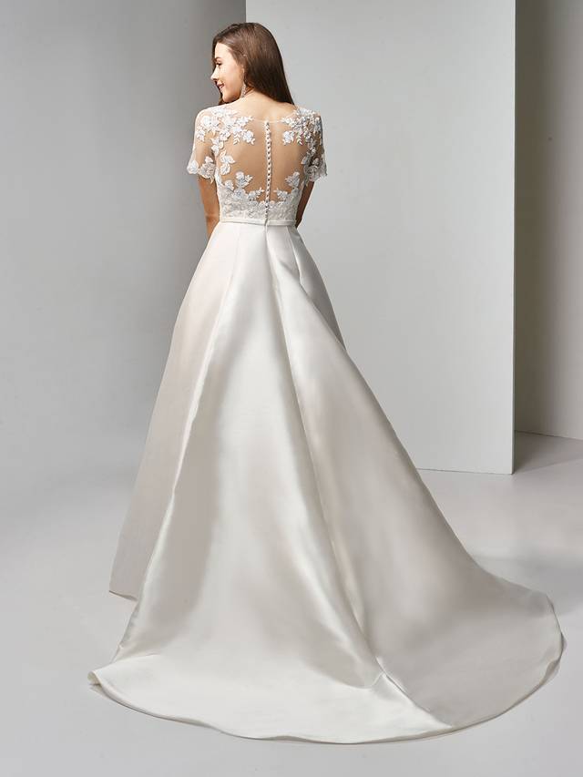 Code: Enzoani Beautiful BT19-15 Code: Enzoani Beautiful BT19-15 Classic with a modern twist -- this full-length, A-line gown is the picture of sweet romance. Delicate embroidered lace is sweet combined with timeless illusion short sleeves and a matching illusion scoop sweetheart neckline. The soft and sleek mikado/satin skirt is accented with a band at the waist to flatter the figure. Finished with covered buttons and an invisible back zipper closure.Colour Options : Ivory