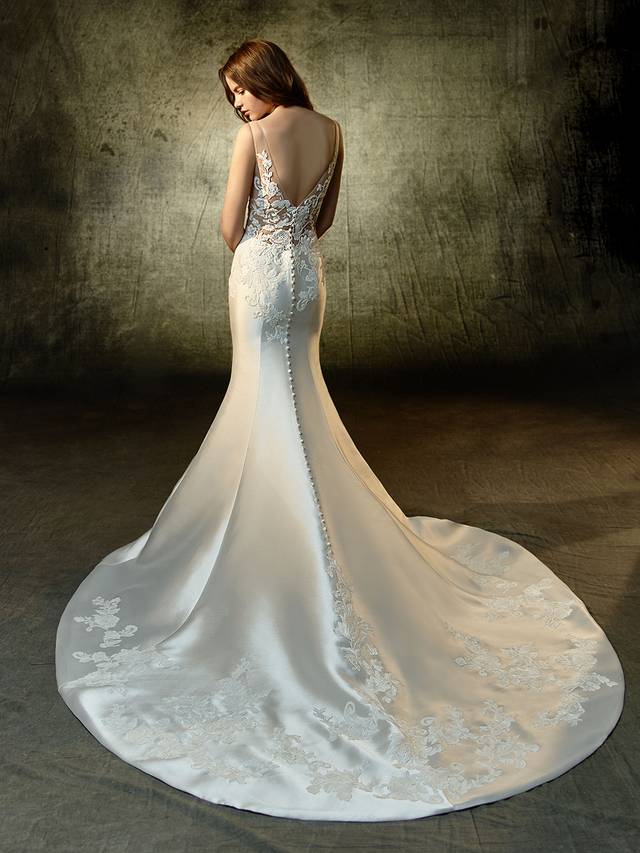 Code: Enzoani Blue Lane Code: Enzoani Blue Lane A haute masterpiece of embroidered lace and mikado fabric, this mermaid gown is an absolute stunner front and back. The deep illusion V-neck creates an exciting break from the ornate bodice that complements the stunning illusion back rich in gorgeous appliques. Covered buttons flow perfectly into the sleekly structured train that ties together the splendor of the gown.Colour Options : Ivory/Champagne OR Ivory/Ivory