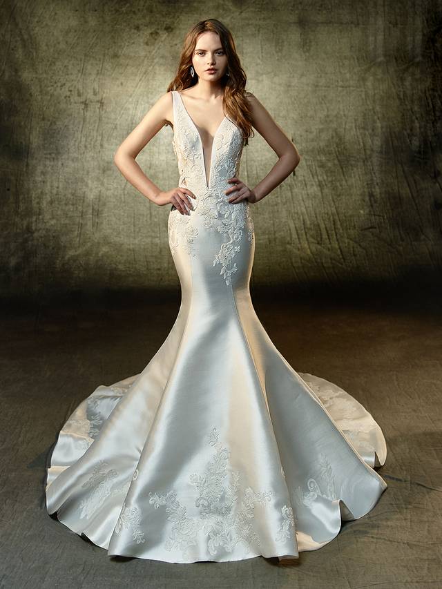 Code: Enzoani Blue Lane Code: Enzoani Blue Lane A haute masterpiece of embroidered lace and mikado fabric, this mermaid gown is an absolute stunner front and back. The deep illusion V-neck creates an exciting break from the ornate bodice that complements the stunning illusion back rich in gorgeous appliques. Covered buttons flow perfectly into the sleekly structured train that ties together the splendor of the gown.Colour Options : Ivory/Champagne OR Ivory/Ivory