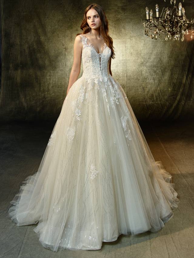 Code: Enzoani Blue Langley Code: Enzoani Blue Langley Delicate but not short on the sparkle factor, this full A-line gown will dazzle and delight the sweetest bride. The illusion V-neck bodice is adorned with graceful lace details that lead to a gorgeous illusion open back that mimics the same details. A spectacular unity of sequin embroidered lace, chantilly lace and sequin tulle adds a touch of play and whimsy to a beautifully timeless silhouette.Colour Options : Ivory/Beige OR Ivory/Ivory
