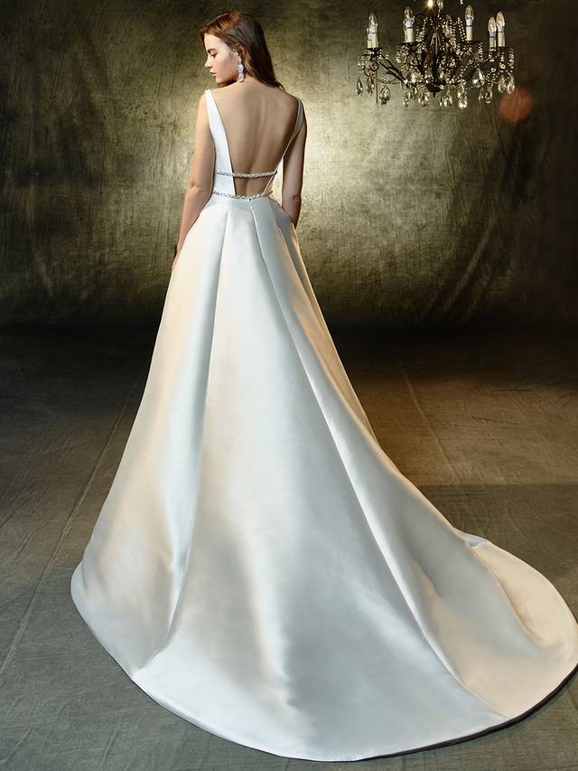 Code: Enzoani Blue Leandra Code: Enzoani Blue Leandra A classic, A-line princess gown with gorgeous, contemporary updates. This full-length, sleek mikado gown features a plunging illusion sweetheart neckline that meets two sparkling, thin rhinestone bands to create the most figure-flattering, waist-cinching effect. A low, open back provides even more modern sexiness.Cololur Options : Ivory/Nude OR Ivory/Ivory