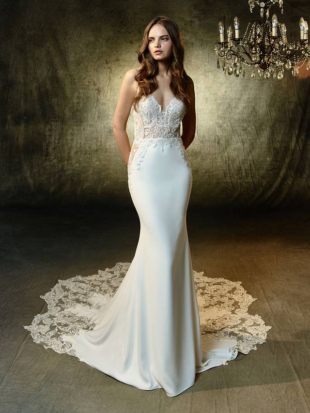 Code: Enzoani Blue Lena Code: Enzoani Blue Lena Sulty mermaid gown with the most exquisite beaded, embroidered lace sweetheart bodice. Dazzling rhinestones frame the deep, illusion V-back that also features the sweetest keyhole effect. Intricate lace flows from the gorgeous train and completes this mesmerizing gown.Collour Options : Ivory/Beige OR Ivory/Ivory