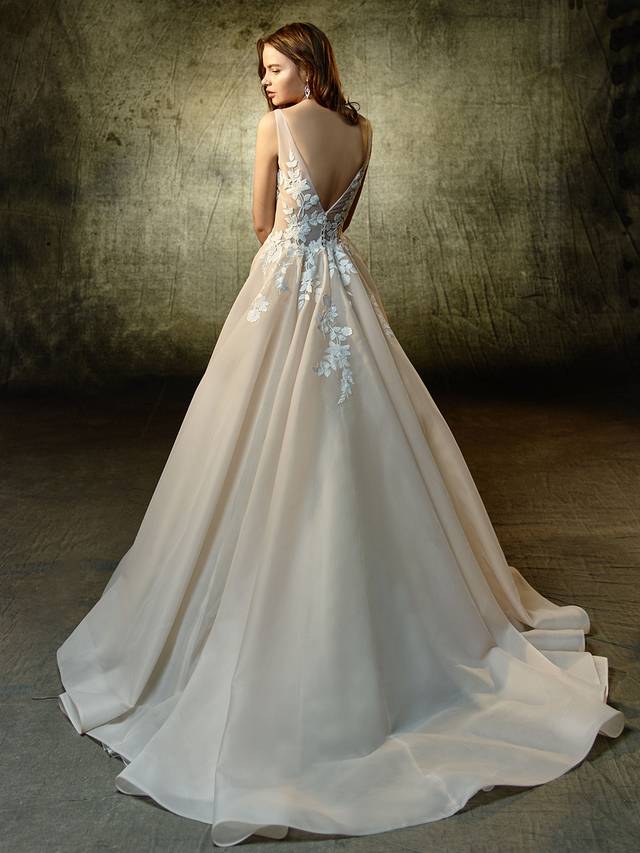 Code: Enzoani Blue Lennox Code: Enzoani Blue Lennox Simply sweet and divine, this full A-line gown is sure to captivate with embroidered floral lace that beautifully flows throughout the deep, unlined illusion V-neckline bodice and soft organza skirt. The unlined, low V-back complements the front as it continues with a sweet V-back embellished with delicate crystal buttons.Colour Options : Dark Ivory/Ivory OR Ivory/Ivory