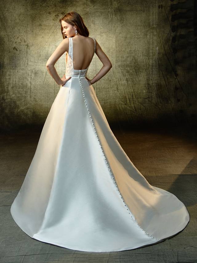 Code: Enzoani Blue Lilybeth Code: Enzoani Blue Lilybeth Equal parts classic and modern, this full-length, A-line gown balances a contemporary embroidered lace and chantilly lace bodice and a sleek, chic mikado skirt. A deep V-neckline is gorgeously trimmed with lace to match the lace bands cinching the waist. The low, open back is perfectly framed with lace straps, while covered buttons trailing down the length of the skirt and train provide the sweet, eye-catching finishing detail.Colour Options : Ivory/Nude OR Ivory/Ivory