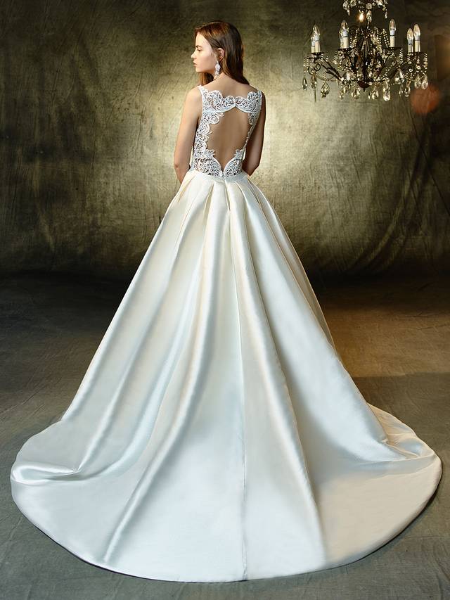 Code: Enzoani Blue Lisette Code: Enzoani Blue Lisette The perfect gown for a fairytale affair -- this full, A-line gown is the picture of modern elegance. Soft, sleek mikado fabric is enhanced with a striking, plunging sweetheart neckline and a band at the waist to create the most flattering figure. Complementing the chic front is a jaw-dropping keyhole back made with exquisite Venice lace. Finished with an invisible back zipper.Colour Options : Ivory/Nude OR Ivory/Ivory