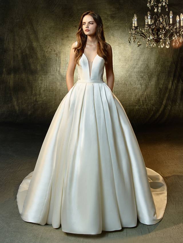 Code: Enzoani Blue Lisette Code: Enzoani Blue Lisette The perfect gown for a fairytale affair -- this full, A-line gown is the picture of modern elegance. Soft, sleek mikado fabric is enhanced with a striking, plunging sweetheart neckline and a band at the waist to create the most flattering figure. Complementing the chic front is a jaw-dropping keyhole back made with exquisite Venice lace. Finished with an invisible back zipper.Colour Options : Ivory/Nude OR Ivory/Ivory