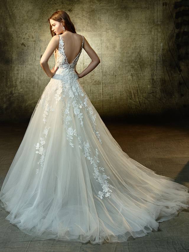 Code: Enzoani Blue Lourdes - IN STUDIO Code: Enzoani Blue Lourdes - IN STUDIO Bring out your inner fairytale princess in this full-length, A-line gown adorned with the sweetest beaded, embroidered lace and chantilly lace. An alluring deep V-neckline on the illusion bodice is perfect paired with illusion side panels and a low V-back. Complete with the dreamiest tulle train and invisbile back zipper closure.Colour Options : Ivory/Nude OR Ivory/Ivory