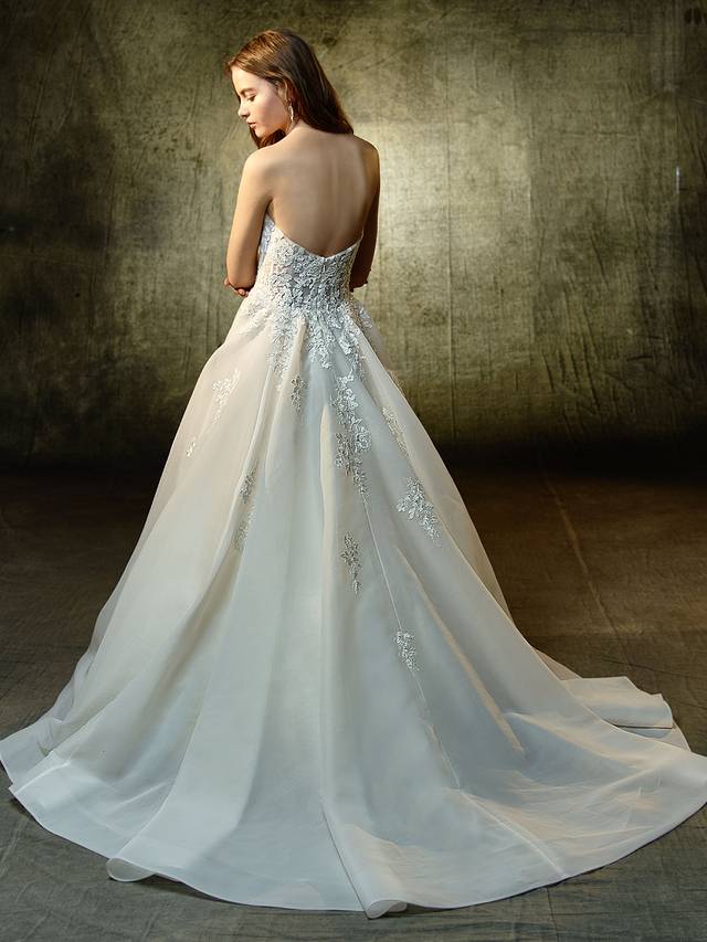 Code: Enzoani Blue Lyvia - IN STUDIO Code: Enzoani Blue Lyvia - IN STUDIO Polished, pretty, and picture-perfect. This full A-line gown features a plunging strapless sweetheart neckline illusion bodice with sparkling beaded, embroidered lace sprinkling down to the dreamy organza skirt. A complementary illusion lace back is finished with an invisible back zipper closure.Colour Options : Dark Ivory/Ivory OR Ivory/Ivory
