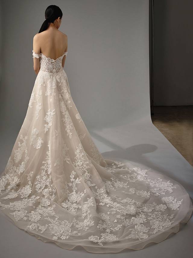 Code: Enzoani Blue - Mariane Code: Enzoani Blue - Mariane A gown made for the modern fairytale ending. This A-line gown features detachable floral off-shoulder sleeves with a sweetheart neckline for the ultimate romantic look. Lace cascades from the bodice to the tulle skirt and train of the gown making it something out of a dream.Colour Options: Ivory/Beige/Nude OR Ivory/Ivory/Ivory OR Ivory/Ivory/Nude