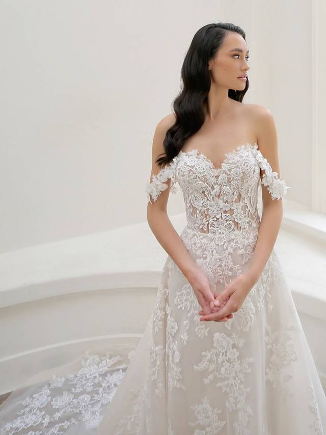 Code: Enzoani Blue - Mariane - IN STUDIO Code: Enzoani Blue - Mariane - IN STUDIO A gown made for the modern fairytale ending. This A-line gown features detachable floral off-shoulder sleeves with a sweetheart neckline for the ultimate romantic look. Lace cascades from the bodice to the tulle skirt and train of the gown making it something out of a dream.Colour Options: Ivory/Beige/Nude OR Ivory/Ivory/Ivory OR Ivory/Ivory/Nude