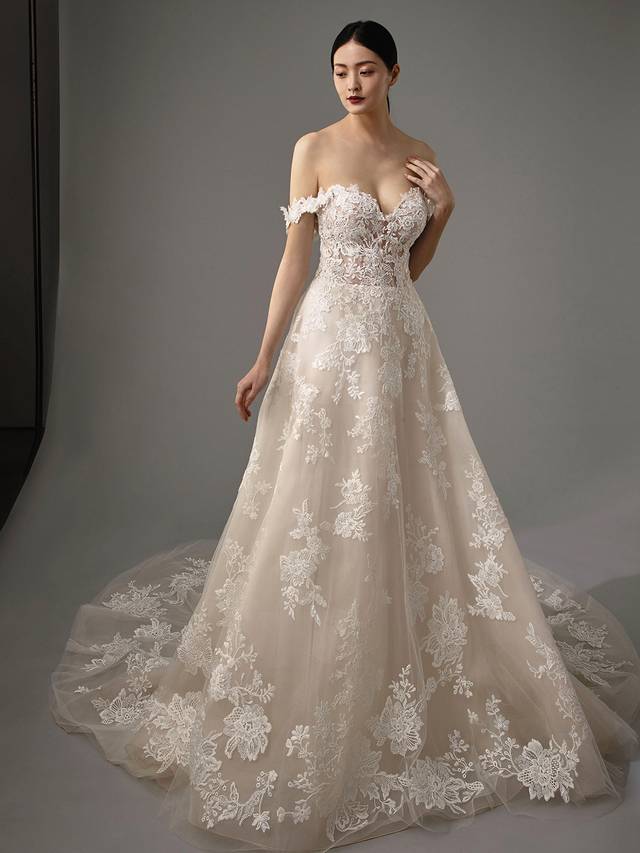 Code: Enzoani Blue - Mariane Code: Enzoani Blue - Mariane A gown made for the modern fairytale ending. This A-line gown features detachable floral off-shoulder sleeves with a sweetheart neckline for the ultimate romantic look. Lace cascades from the bodice to the tulle skirt and train of the gown making it something out of a dream.Colour Options: Ivory/Beige/Nude OR Ivory/Ivory/Ivory OR Ivory/Ivory/Nude
