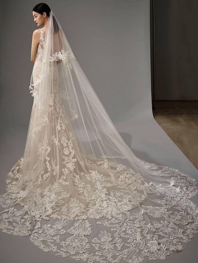 Code: Enzoani Blue - Marianna with Veil Code: Enzoani Blue - Marianna with Veil Vintage and classic meets modern and sultry. Regal lace covers this mermaid gown as it is carefully placed between the bodice, tulle skirt and train. Its low V-neckline is complemented by its low, sultry V-back, complete with a trail of covered buttons. A lace train finishes the look for a modern, romantic touch. Pair this gown with its veil.Colour Options: Ivory/Beige/Nude OR Ivory/Ivory/Ivory OR Ivory/Ivory/Nude OR Ivory/Nude/Nude