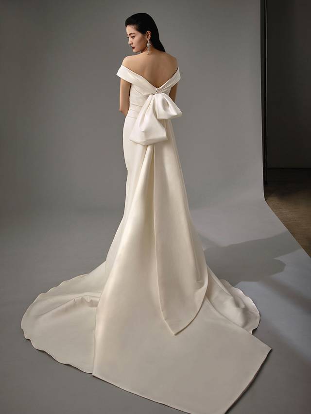 Code: Enzoani Blue - Marla Code: Enzoani Blue - Marla Feminine and elegant are all wrapped into one gown. Soft stretch mikado is gorgeously crafted to create this off-shoulder mermaid gown. A sweetheart neckline and ruched fabric at the side both flatters and enhances. Final touches are added with the gown's detachable statement bow.Colour Options: Ivory