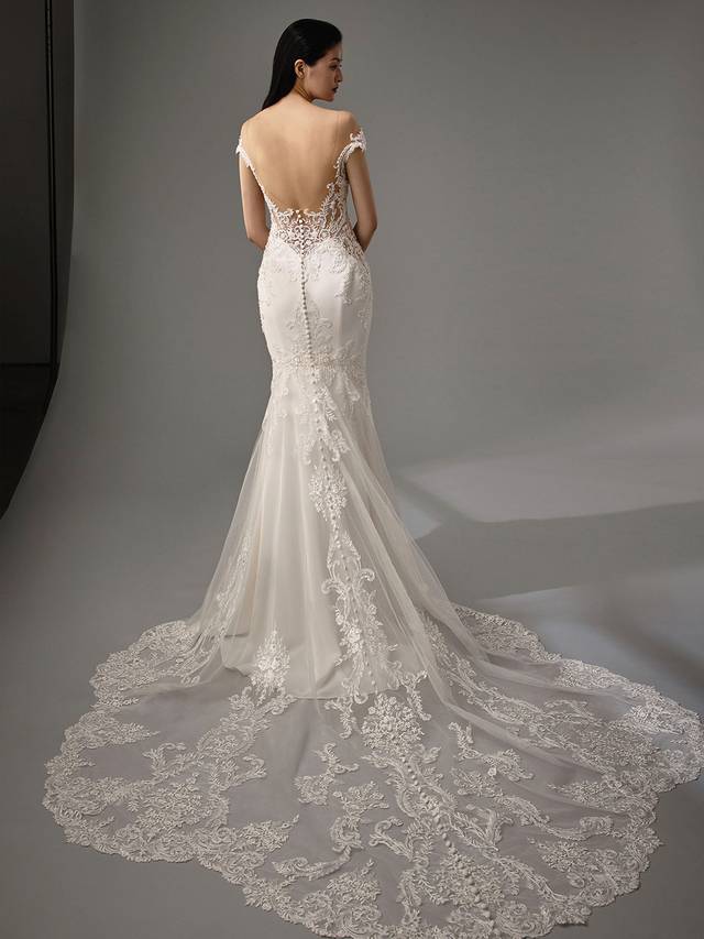 Code: Enzoani Blue - Marquise Code: Enzoani Blue - Marquise Elegance and romance are packed into one gorgeous stretch georgette gown. Alluring lace illusion panels on the sides are sure to highlight a bride's figure. Lace is carefully placed on the sweetheart neckline as it trails to the thigh. An alluring, low illusion back finishes the look with covered buttons cascading to the train's hem.Colour Options: Ivory/Nude OR Ivory/Ivory
