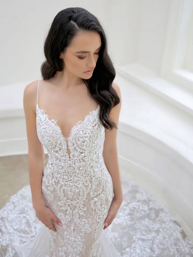 Code: Enzoani Blue - Martina - IN STUDIO Code: Enzoani Blue - Martina - IN STUDIO Dreamy and oh so romantic, this classic all-over lace mermaid gown is what you've been waiting for. Regal lace starts at the bodice with a low, plunging neckline. It cascades down to the tulle train with a delicate lace hem. A ruched bottom and covered buttons add a hint of playfulness Finished with a sexy, low V-back.Colour Options: Ivory/Nude/Nude OR Ivory/Ivory/Ivory OR Ivory/Ivory/Nude OR Ivory/Sand/Nude