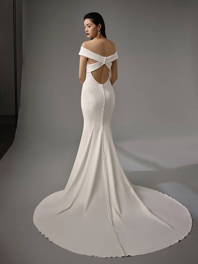 Code: Enzoani Blue - Maylin Code: Enzoani Blue - Maylin Chic and elegant, this gown was made for the modern bride. Soft crepe is used to create its mermaid silhouette, while off-shoulder details offer feminine touches along with a criss-cross keyhole back for added playfulness. Cascading covered buttons complete the ultimate sophisticated look.Colour Options: Ivory