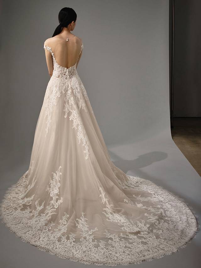 Code: Enzoani Blue - Micah Code: Enzoani Blue - Micah Made for a fairytale wedding, this A-line gown is irresistible with its gorgeous lacy bodice and airy tulle layers. A sweethaert neckline and illusion, off-the-shoulder lace sleeves add even more romance, while covered buttons subtly highlight the striking illusion low back.Colour Options: Ivory/Beige/Nude OR Ivory/Ivory/Ivory OR Ivory/Ivory/Nude