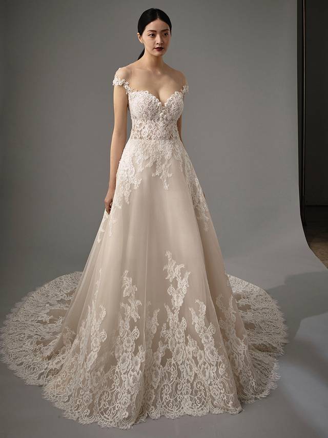 Code: Enzoani Blue - Micah Code: Enzoani Blue - Micah Made for a fairytale wedding, this A-line gown is irresistible with its gorgeous lacy bodice and airy tulle layers. A sweethaert neckline and illusion, off-the-shoulder lace sleeves add even more romance, while covered buttons subtly highlight the striking illusion low back.Colour Options: Ivory/Beige/Nude OR Ivory/Ivory/Ivory OR Ivory/Ivory/Nude