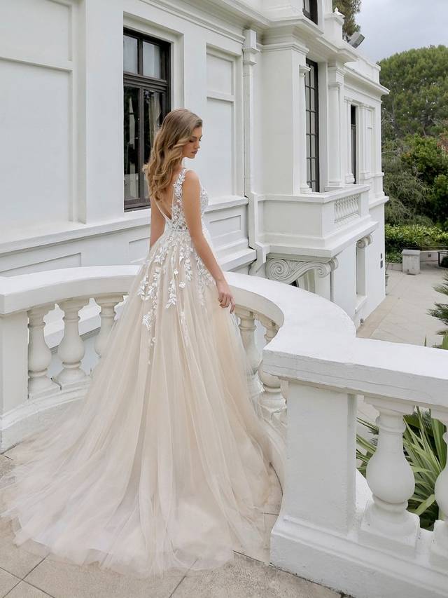 Code: Enzoani Blue - Mikayla - IN STUDIO Code: Enzoani Blue - Mikayla - IN STUDIO Sweet and ethereal, this A-line gown features a plunging neckline on a gorgeous chantilly lace bodice. Lace continues to cascade gently onto dreamy tulle layers of the skirt. Whimsical and romantic, Mikayla also features an open V-back with covered buttons and an invisible zipper closure.Colour Options: Ivory/Beige/Nude OR Ivory/Ivory/Ivory OR Ivory/Ivory/Nude