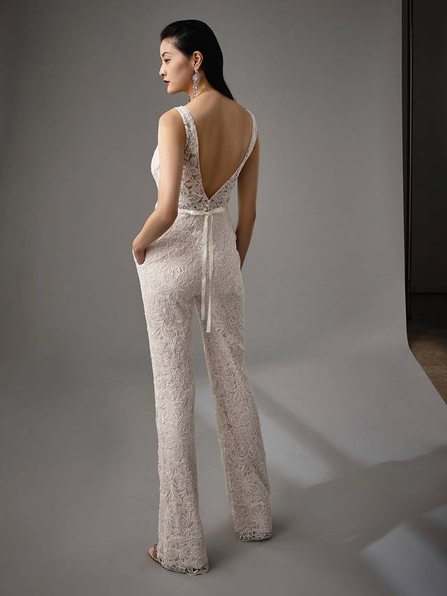 Code: Enzoani Blue - Myelle Code: Enzoani Blue - Myelle Take this look from sweet and whimsical to modern boho in seconds. This two-in-one piece changes from an A-line gown to edgy jumpsuit. Soft, airy layers of tulle can be added just by attaching the skirt onto the jumpsuit, while the jumpsuit itself offers a plunging neckline and sweet ribbon belt at the waist.Colour Options: Ivory/Sand OR Ivory/Ivory OR Ivory/Nude