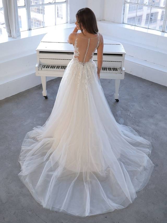 Code: Blue By Enzoani Nasrin Code: Blue By Enzoani Nasrin Fall in love with the enchanting NASRIN gown. A beaded, embroidered lace bodice cascades down the hips to complement layers of beautiful organza and tulle. The boning in the bodice provides that desired structure in an A-line style. An illusion back and crystal buttons framed by a symmetrical lace pattern will leave you feeling like effortlessly elegant.Colour Options: Ivory/Sand/Nude OR Ivory/Ivory/Ivory OR Ivory/Ivory/Nude OR Ivory/Nude/Nude