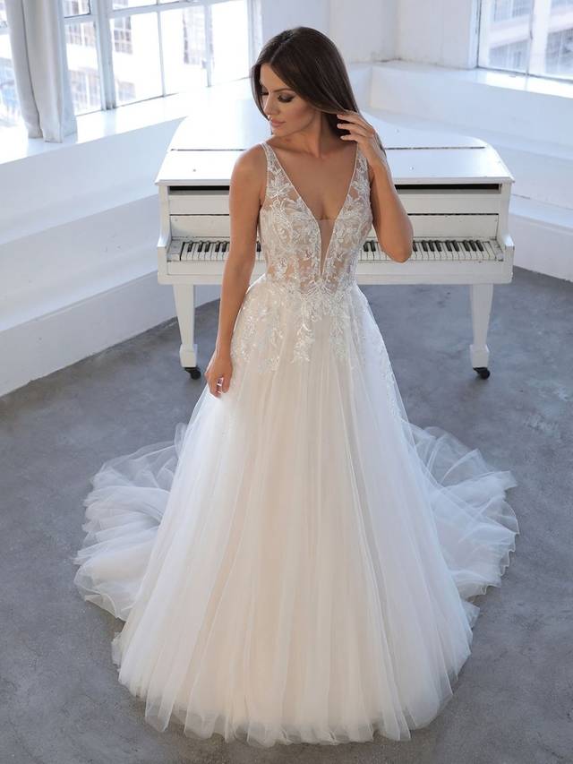 Code: Blue By Enzoani Nasrin Code: Blue By Enzoani Nasrin Fall in love with the enchanting NASRIN gown. A beaded, embroidered lace bodice cascades down the hips to complement layers of beautiful organza and tulle. The boning in the bodice provides that desired structure in an A-line style. An illusion back and crystal buttons framed by a symmetrical lace pattern will leave you feeling like effortlessly elegant.Colour Options: Ivory/Sand/Nude OR Ivory/Ivory/Ivory OR Ivory/Ivory/Nude OR Ivory/Nude/Nude