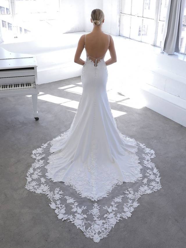 Code: Enzoani Blue Nigella Code: Enzoani Blue Nigella This mermaid gown is the perfect mix of sweet, sleek, and sexy. A beautiful bodice of floral embroidered lace and chantilly lace complements the light, flowy crepe skirt for a modern and romantic look. The slim, plunging front V-neckline is balanced by the low illusion back with delicate beading for a hint of shimmer.Colour Options: Ivory/Nude OR Ivory/Ivory