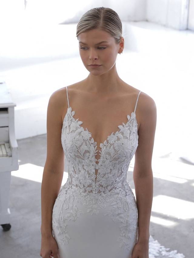 Code: Enzoani Blue Nigella Code: Enzoani Blue Nigella This mermaid gown is the perfect mix of sweet, sleek, and sexy. A beautiful bodice of floral embroidered lace and chantilly lace complements the light, flowy crepe skirt for a modern and romantic look. The slim, plunging front V-neckline is balanced by the low illusion back with delicate beading for a hint of shimmer.Colour Options: Ivory/Nude OR Ivory/Ivory