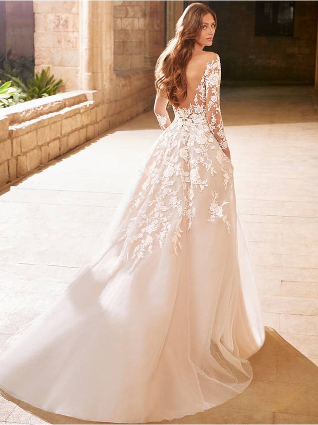 Code: Etoile Arabelle - IN STUDIO Code: Etoile Arabelle - IN STUDIO This classic, long sleeve ballgown features a semi-constructed bodice with a sexy, plunging neckline and low back. Gorgeous, sparkling and floral botanical lace wraps around the body and illusion sleeves before cascading elegantly into the soft, slim A-line skirt.Colour Options: Ivory/Nude/Nude OR Ivory/Ivory/Nude