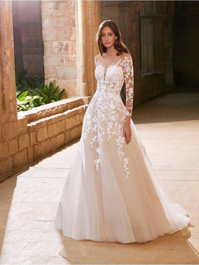 Code: Etoile Arabelle - IN STUDIO Code: Etoile Arabelle - IN STUDIO This classic, long sleeve ballgown features a semi-constructed bodice with a sexy, plunging neckline and low back. Gorgeous, sparkling and floral botanical lace wraps around the body and illusion sleeves before cascading elegantly into the soft, slim A-line skirt.Colour Options: Ivory/Nude/Nude OR Ivory/Ivory/Nude