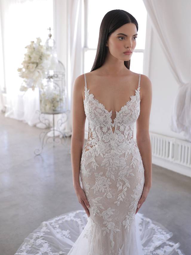 Code: Blue By Enzoani Olana Code: Blue By Enzoani Olana Like a gorgeous upgrade on our beloved Nadia gown. Combined with sparkling sequined Chantilly lace, the beloved thick embroidered floral lace stands out even more with figure-enhancing illusion side panels and the low, open illusion lace back. The detachable, off-shoulder lace and tulle split cape creates even more jaw-dropping drama. Colour Options: Ivory/Nude/Nude OR Ivory/Ivory/Nude OR Ivory/Sand/Nude OR Ivory/Ivory/Ivory
