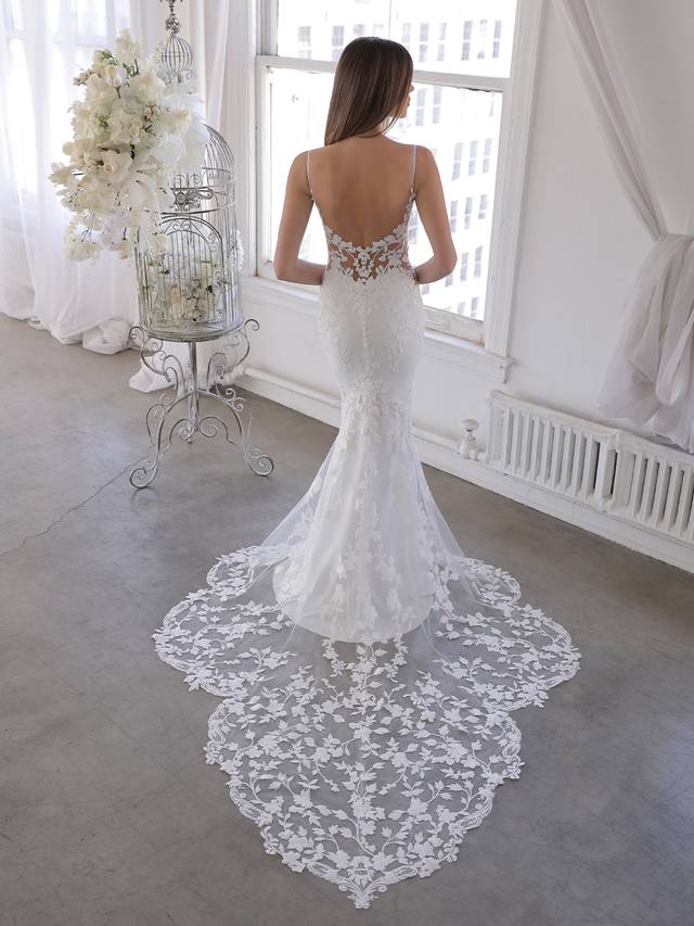 Code: Enzoani Blue Oliviana - ARRIVING SOON Code: Enzoani Blue Oliviana - ARRIVING SOON This gorgeous mermaid gown features the sought-after thick floral embroidered lace of bestselling styles on a plunging illusion sweetheart neckline bodice with sweet spaghetti straps. The illusion lace back is sure to keep all eyes on the bride, especially with the lace beautifully cascading down the softest stretch georgette and tulle skirt featuring a signature Enzoani scalloped lace train. Colour Options: Ivory/Nude OR Ivory/Ivory