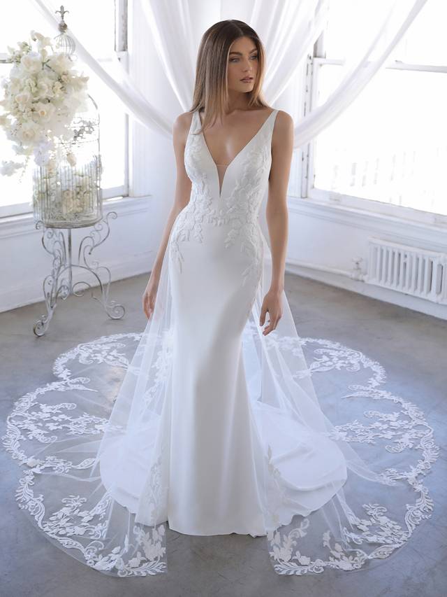 Code: Enzoani Blue Ozalea (with train) Code: Enzoani Blue Ozalea (with train) Ozalea is for the modern bride who wants the best of both worlds – clean and simple but also dramatic and showstopping. A detachable tulle and lace train is perfect for added splendor for the ceremony and wedding photos, and can be removed to reveal a sleek and elegant stretch georgette silhouette. Thick floral embroidered lace provides gorgeous detailing to accentuate the sexy plunging V-neckline and low illusion back.Colour Options: Ivory/Nude OR Ivory/Ivory