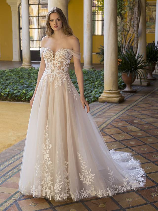 Code: Blue By Enzoani Paula Code: Blue By Enzoani Paula Simply sweet and divine, this stunning A-line gown is sure to captivate with the custom-made, vine-like 3D embroidered motifs that beautifully flow throughout the deep, illusion sweetheart corset-style bodice and lavish tulle skirt. A layer of glitter texture underneath brings subtle sparkle to complement the dreamy layers of soft tulle and organza. The artfully draped, detachable off-the-shoulder tulle straps complete the romantic look.Colour Options: Ivory/Beige/Nude OR Ivory/Ivory/Ivory OR Ivory/Ivory/Nude