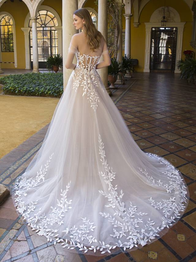 Code: Blue By Enzoani Paula Code: Blue By Enzoani Paula Simply sweet and divine, this stunning A-line gown is sure to captivate with the custom-made, vine-like 3D embroidered motifs that beautifully flow throughout the deep, illusion sweetheart corset-style bodice and lavish tulle skirt. A layer of glitter texture underneath brings subtle sparkle to complement the dreamy layers of soft tulle and organza. The artfully draped, detachable off-the-shoulder tulle straps complete the romantic look. Colour Options: Ivory/Beige/Nude OR Ivory/Ivory/Ivory OR Ivory/Ivory/Nude