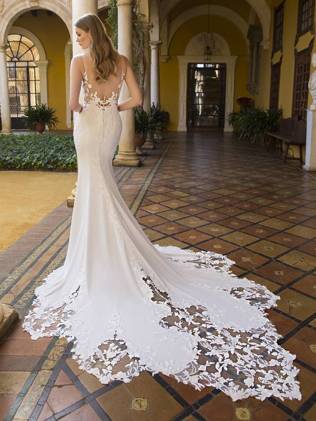 Code: Blue By Enzoani Princess Code: Blue By Enzoani Princess Feel effortlessly beautiful and modern when you meet this elegant, sheath style wedding dress. Intricate bespoke, bold floral motif lace travels from the romantic V-plunge illusion neckline to a spectacular corset-style bodice and low illusion back down to the soft and sleek stretch georgette skirt. The gorgeous scalloped lace cut hem is sure to easily catch everyone’s attention – ideal for those heart-stopping back photos and dramatic entrances. Colour Options: Ivory/Nude OR Ivory/Ivory