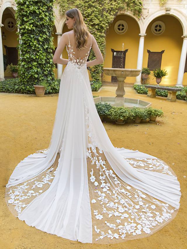 Code: Enzoani Blue Parker Code: Enzoani Blue Parker Feminine and sweet, this floaty, soft A-line gown is complete with layers of sheer chiffon skirt, a V-plunge illusion corset-style bodice with an open back, and the most gorgeous, whimsical cascading tulle trains covered in delicate botanical appliques. This unique composing of exquisite laser-cut 3D lace and customized embroidered wild floral motifs trails from the bodice to its skirt, while the back slowly opens to show off a glamorous, dramatic train. Colour Options: Ivory/Nude OR Ivory/Ivory