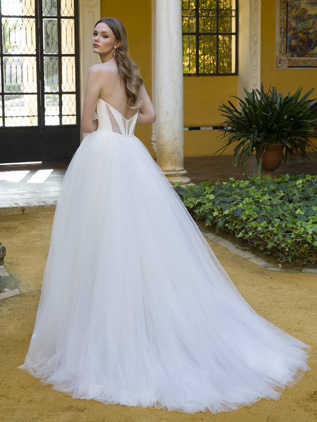 Code: Enzoani Blue Penina Code: Enzoani Blue Penina This stunning look is the perfect balance between simplicity and whimsy. Featuring a V-plunge illusion sweetheart neckline, a boned ivory padded corset-style bodice, and combined with dazzling beaded texture sheer panels, it lends a modern edge and eye-catching effects to this fairytale-like tulle ball gown.Colour Options: Ivory/Nude OR Ivory/Ivory