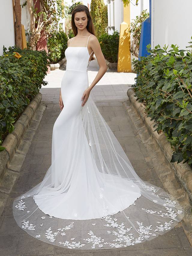 Code: Love By Enzoani Belle Code: Love By Enzoani Belle Sweet simplicity with a side of sexy. BELLE is as beautiful as minimalism can get. This lightweight stretch georgette gown offers an elegant silhouette featuring thin spaghetti straps and a flattering, modern square neckline to bring contemporary sophistication. The low illusion back is adorned in exquisite floral embroidered lace that cascades down from a daring, open sheer back to an unforgettable, sweeping tulle train. Colour Options: Ivory/Nude OR Ivory/Ivory