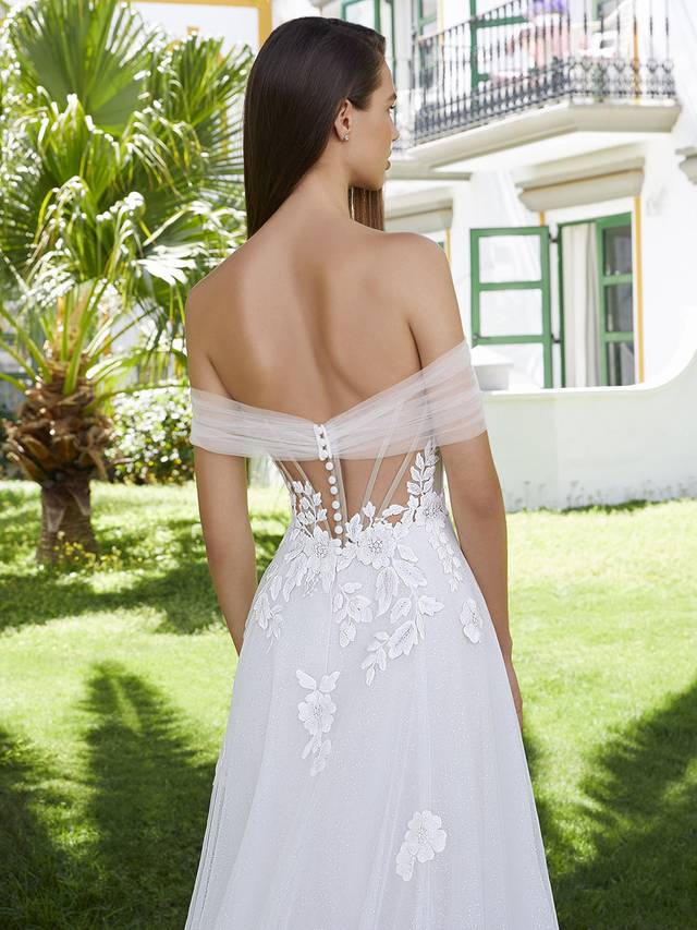 Code: Love By Enzoani Bernadine Code: Love By Enzoani Bernadine BERNADINE effortlessly exudes romance. The soft sweetheart neckline is elegantly balanced with dreamy off-the-shoulder tulle sleeves, a sexy illusion corset style bodice with exposed boning and delicately scattered floral embroidered lace that drapes onto an ethereal glitter tulle skirt. The tulle draping detail across the appliques adds even more eye-catching flair to this uniquely sweet and modern gown. Colour Options: Ivory/Beige/Nude OR Ivory/Ivory/Ivory OR Ivory/Ivory/Nude