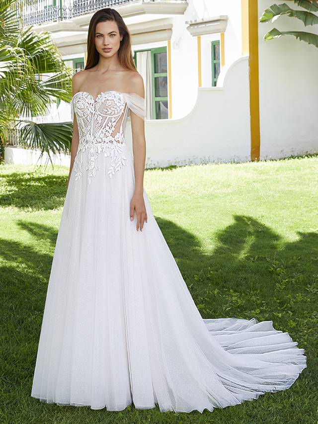 Code: Love By Enzoani Bernadine Code: Love By Enzoani Bernadine BERNADINE effortlessly exudes romance. The soft sweetheart neckline is elegantly balanced with dreamy off-the-shoulder tulle sleeves, a sexy illusion corset style bodice with exposed boning and delicately scattered floral embroidered lace that drapes onto an ethereal glitter tulle skirt. The tulle draping detail across the appliques adds even more eye-catching flair to this uniquely sweet and modern gown.Colour Options: Ivory/Beige/Nude OR Ivory/Ivory/Ivory OR Ivory/Ivory/Nude