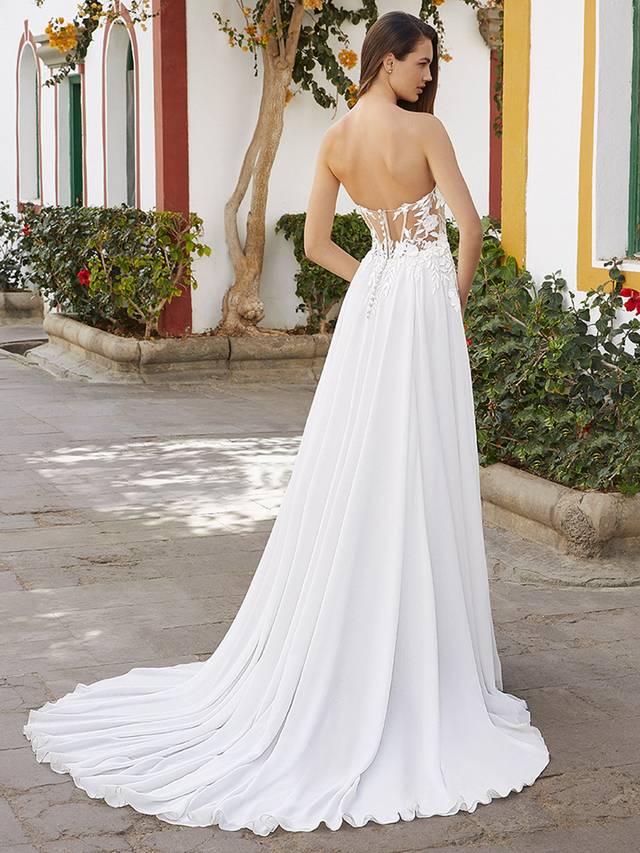 Code: Love By Enzoani Bethenny Code: Love By Enzoani Bethenny Timeless elegance with a romantic twist. BETHENNY features a sultry V-plunging illusion neckline on a corset style bodice framed with thick, intricate embroidered floral embroidered lace and delicate buttons on the back. The gown is balanced with a multi-layered, flowy chiffon skirt which is elevated with a showstopping modern slit for added subtle sexiness. Colour Options: Ivory/Nude OR Ivory/Ivory