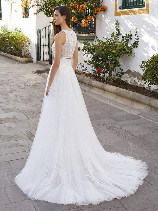Code: Love By Enzoani Brystol-A Code: Love By Enzoani Brystol-A Who says the bride has to wear a one-piece gown? Brystol-A gives a girl choice! Glisten like no other in this beautifully beaded, cropped style bodice, complete with clear buttons for a sexy touch.Brystol-A’s soft tulle, A-Line skirt features a wide waist band that cinches and flatters the figure for a super chic two-piece bridal look. Colour Options: Ivory/Nude OR Ivory/Ivory