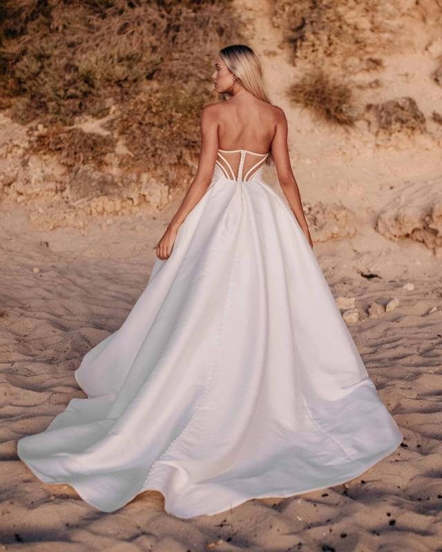 Code: Blue By Enzoani Peggy (Without Sleeve) Code: Blue By Enzoani Peggy (Without Sleeve) Minimalist bride meets Old Hollywood to create this drop-dead gorgeous ball gown. This Mikado beauty takes front and center stage with a flattering, cinched waistline and ultra-chic, one-shoulder sleeve (and it’s detachable)! For an added touch of glamour and drama, Peggy features an elegant and unique illusion corset back that is truly one-of-a-kind.Colour Options: Ivory/Nude OR Ivory/Ivory