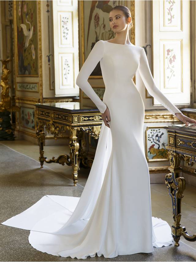 Code: Élysée Atelier Desmond Code: Élysée Atelier Desmond Talk about old Hollywood glamour! DESMOND is a chic, clean and sleek gown for brides who want to look sophisticated and modern in the front with the high-neck column silhouette, and daring in the back with its deep, open V-back. The unique couture-inspired, tie-back draped train detail is the perfect cherry on top to create this sexy and timeless bridal look.Colour Option: Ivory