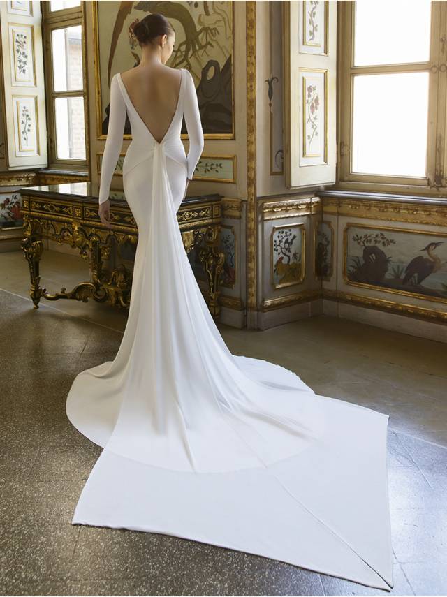 Code: Élysée Atelier Desmond Code: Élysée Atelier Desmond Talk about old Hollywood glamour! DESMOND is a chic, clean and sleek gown for brides who want to look sophisticated and modern in the front with the high-neck column silhouette, and daring in the back with its deep, open V-back. The unique couture-inspired, tie-back draped train detail is the perfect cherry on top to create this sexy and timeless bridal look.Colour Option: Ivory