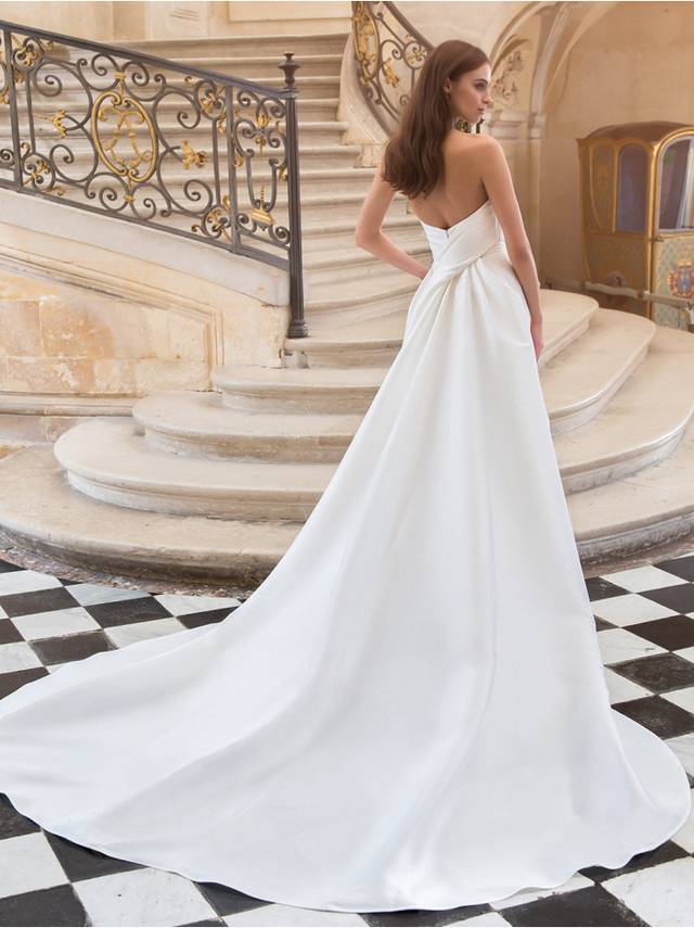 Code: Élysée Vesper Code: Élysée Vesper Timeless yet modern and unique, VESPER is a sleek Mikado mermaid gown with beautiful draping on the classic strapless sweetheart bodice for a stunning, accentuated bridal look. This gown makes a statement with its sophisticated draped back leading to a clean and elegant train.Colour Option: Ivory